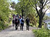 En gruppe personer går på en grusvei gjennom et grønt skogsområde.