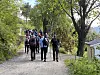 En gruppe personer går på en grusvei gjennom et grønt skogsområde.