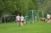 Fotballspillere på en gressbane med mål og en keeper i oransje drakt nær høyre side.