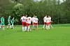 To fotballag i rødt og hvitt står samlet på en grønn fotballbane.