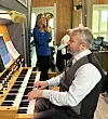 Pianist ved orgel i kirkerom, med to musikere i bakgrunnen og instrumenter rundt.