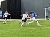 Fotballspillere kjemper om ballen på en grønn gressbane.