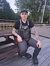 Person i fiskerklær og caps sitter på en treterrasse ved et piknikbord.