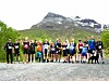En gruppe løpere står samlet på en grusvei foran et fjell.