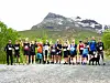 En gruppe løpere står samlet på en grusvei foran et fjell.