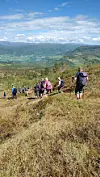 Turgåere går langs en fjellrygg med utsikt over dal og fjell i bakgrunnen.