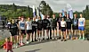 En gruppe løpere står samlet på veien før start.