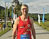 En løper står foran en løype med startnummer og solbriller.