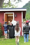 Flere personer står foran en liten rød bygning med åpen dør og titter inn.