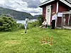 En gutt står og en gutt sitter og ser på at en annen gutt spiller ringspill.