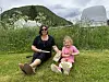 En kvinne og et barn sitter på en grønn plen.