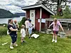 Jente holder to sinkbøtter ut til hver sin side av kroppen. Noen ser på og en tar tiden.