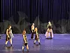 Fem dansere på en scene foran mørke gardiner.