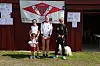 Tre personer står foran en bygning med en Rindal-banner og plakater på veggen.