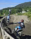 Tre motocross-sykler i et løp på bane.