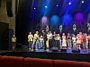 Kor som opptrer på en opplyst scene med blå, lilla og gule scenelys.