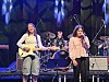 Band spiller på scene med gitarist, trommeslager og vokalist i blått scenelys.