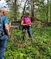 To personer går gjennom tett skog og vegetasjon ved en steinrøys.