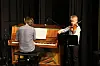 Pianist og ung fiolinist opptrer sammen på en scene med svart bakteppe.
