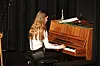 En kvinne sitter ved et piano og spiller på en scene med mørk bakgrunn.