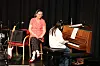 En pianist spiller piano på en scene med en kvinne som sitter ved siden av.