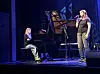 Sanger og pianist på scene med flygel og blå belysning.