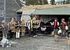 Flere utkledde barn utendørs foran en bygning. En musiker.