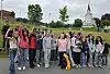 En gruppe mennesker står samlet utendørs foran en kirke og poserer for et gruppebilde.