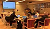 Folk sitter rundt et møtebord i et konferanserom med en presentasjon på skjerm.