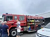 Rød brannbil med åpent utstyrrom og flere personer samlet ved siden av.