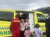 Flere personer går inn i en gul ambulanse med åpen bakdør.
