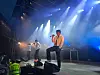 Band opptrer på scene med mikrofoner, lys og røyk i blått scenelys.