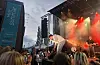 Band spiller på utendørsscene med publikum foran og rødt lys i bakgrunnen.