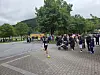 En løper på en parkvei med tilskuere, barnevogn og trær i bakgrunnen.