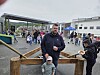 Folk går mellom boder og aktiviteter på et utendørs marked, med en mann og et barn i forgrunnen.