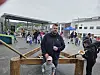 Folk går mellom boder og aktiviteter på et utendørs marked, med en mann og et barn i forgrunnen.