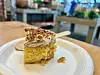 Et stykke kake på hvit tallerken på et bord i en kafé.