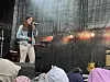 Sanger fremfører på en utendørsscene. Instrumenter og scenelys.