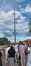 Folkemengde samles ved en høy pyntet stolpe under en skyet himmel.