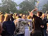 En tett folkemengde står samlet utendørs i kveldslys foran en konsert eller offentlig samling.