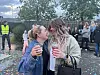 To kvinner klemmer hverandre og holder drikke på et utendørs arrangement.