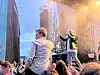 Artist opptrer på utendørsscene foran et publikum i solnedgang.