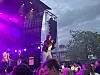 Artist synger på utendørsscene foran publikum i skumringen.