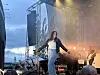 Artist opptrer på en utendørsscene foran publikum ved solnedgang.