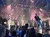 Band opptrer på scene med røyk, lys og gnister foran et tett publikum.