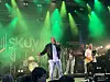 Band opptrer på scene med grønne scenelys og publikum foran.
