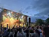 Publikum foran en konsertscene med konfetti i lufta ved solnedgang.