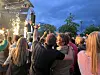 Tett publikum foran en utendørsscene med lys og gnister i skumringen.
