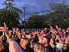 Tett publikum med hendene i været under et utendørsarrangement i skumringen.