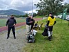 Fire personer med diskgolfutstyr står ved en bane med fjell og grønt landskap i bakgrunnen.
